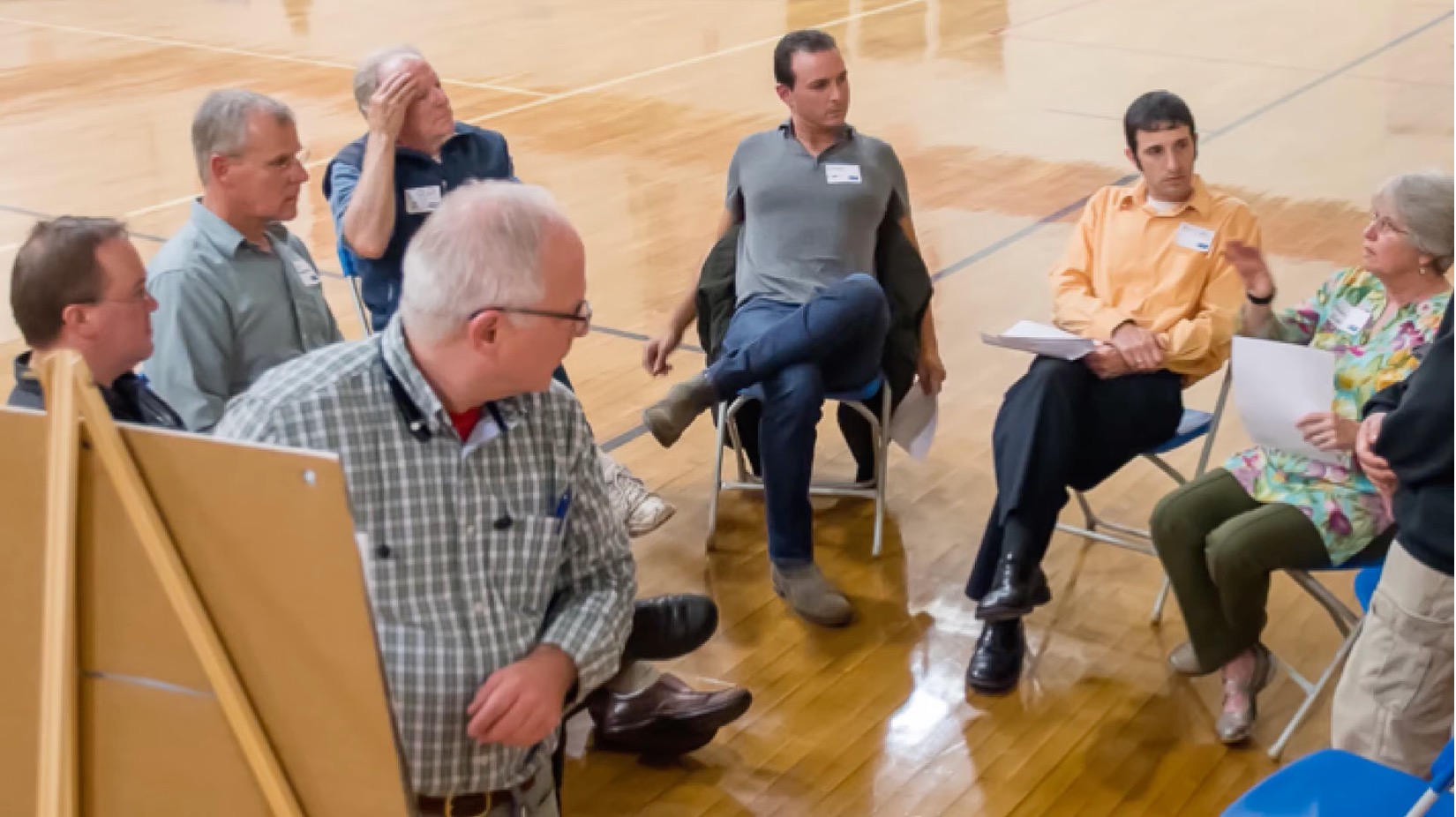 Group of people sitting in circle learning about facilitation skills.